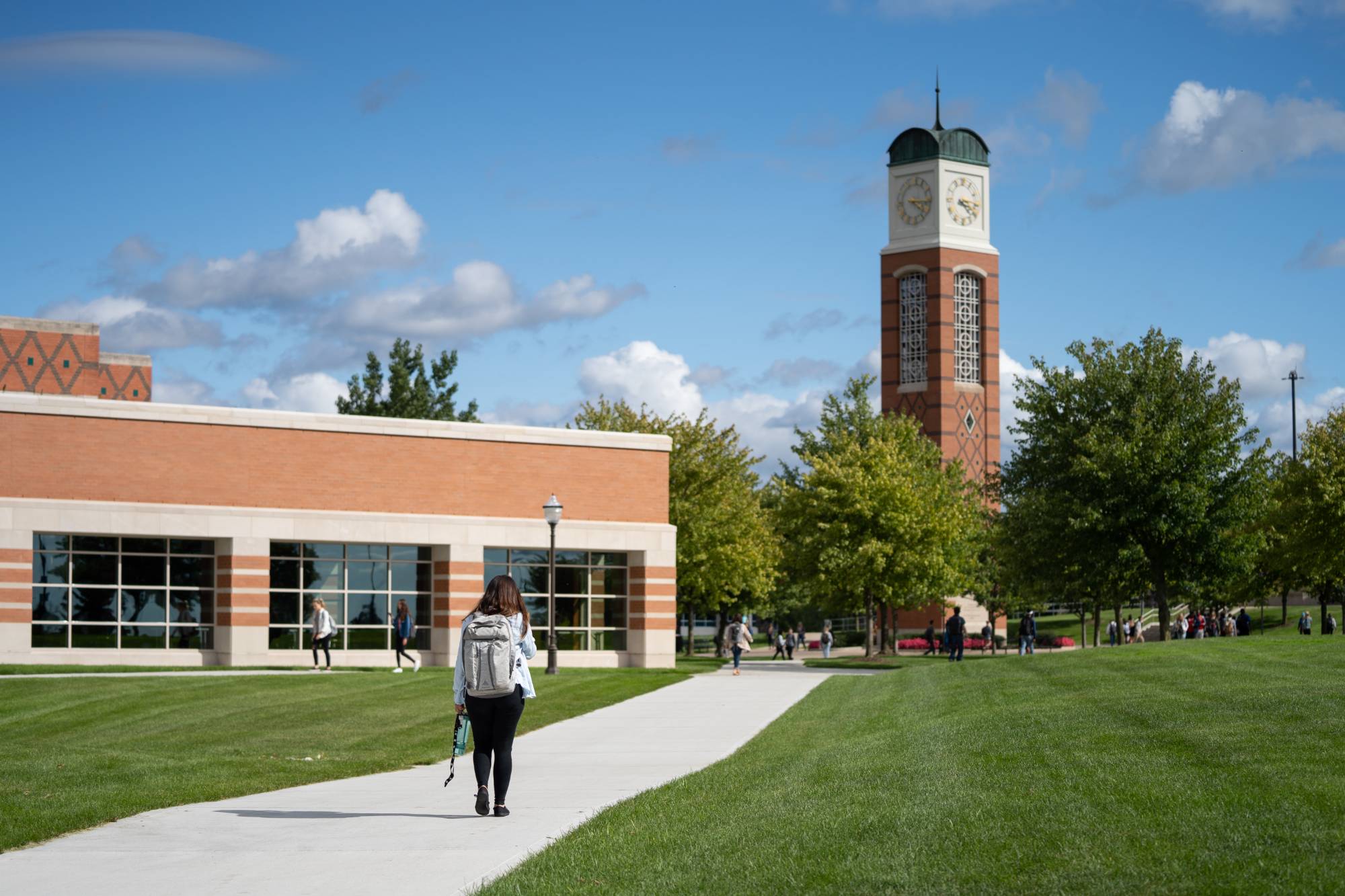 student walks towards GVSU clock tower in spring